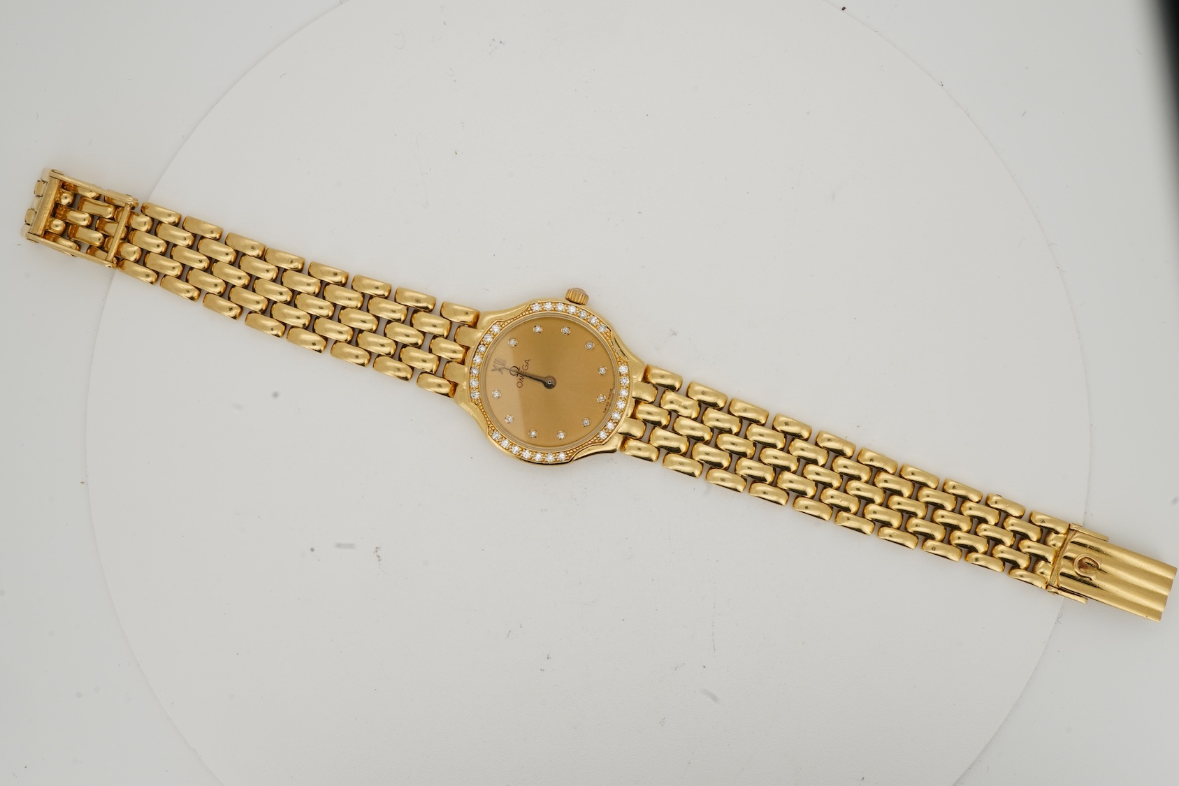 A lady's recent 18ct gold Omega quartz dress wrist watch, with diamond dot markers and diamond set bezel
